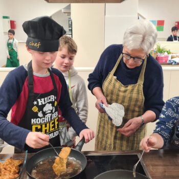 Vier Schüler und eine Lehrerin kochen gemeinsam