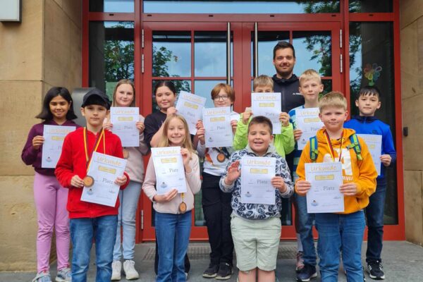 Kinder stehen auf der Treppe und halten ihre Urkunden hoch