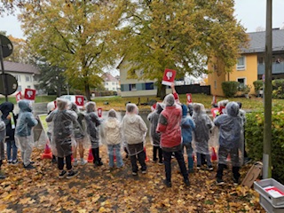 Kinder stehen am Straßenrand und halten Schilder in die Höhe