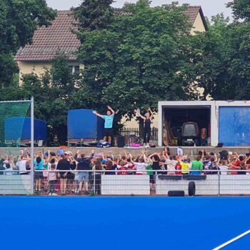 Kinder und 2 Lehrer am BTS Platz beim Aufwärmprogramm