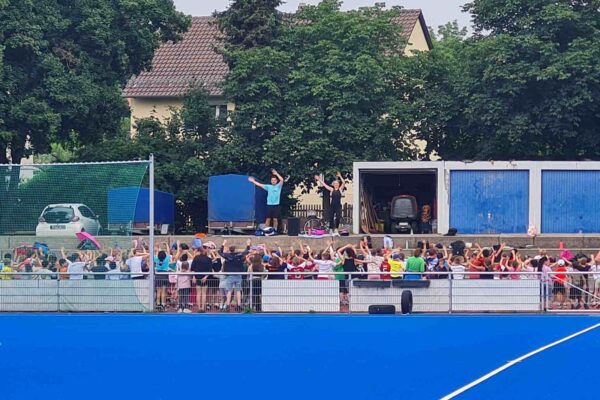 Kinder und 2 Lehrer am BTS Platz beim Aufwärmprogramm