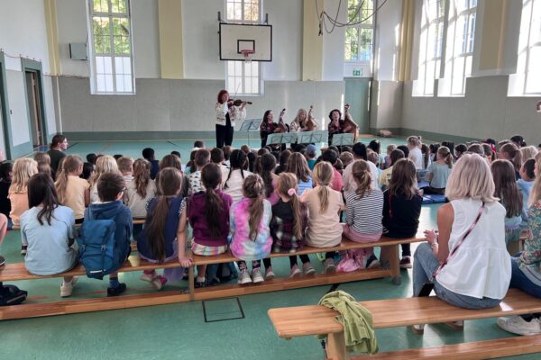 Schüler sitzen in der Turnhalle beim Konzert der Goldkehlchen