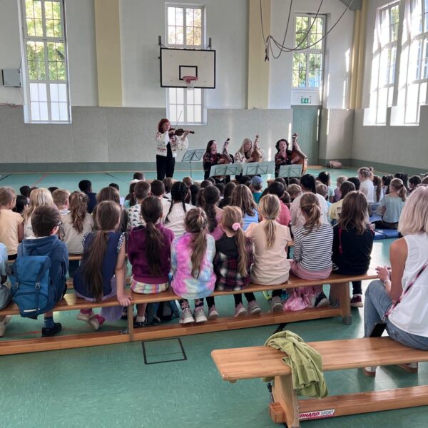 Schüler sitzen in der Turnhalle beim Konzert der Goldkehlchen
