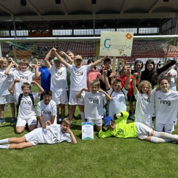 Schüler stehen und liegen auf dem Fußballfeld und jubeln
