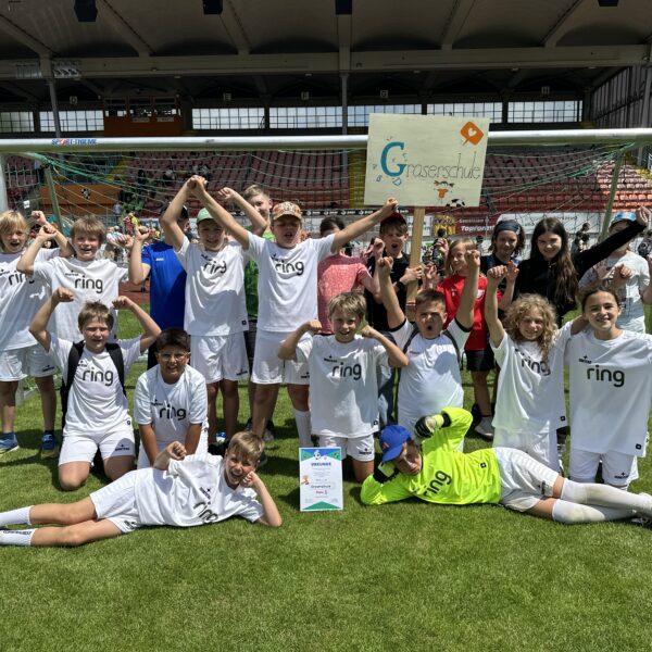 Schüler stehen und liegen auf dem Fußballfeld und jubeln